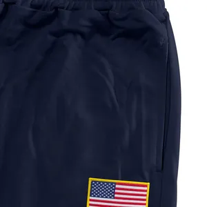 Gros plan détaillé du pantalon de sport bleu marine avec tissu mesh et écusson drapeau USA.