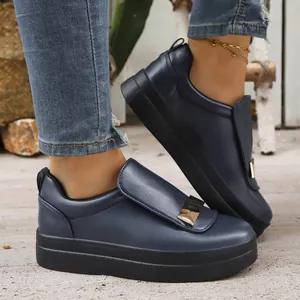 Navy blue women's platform slip-on loafers with decorative gold buckle on rustic ground