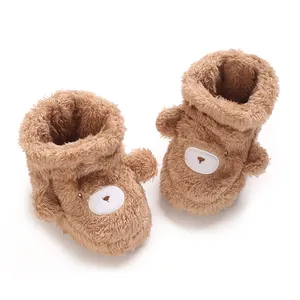 Primer plano de suaves botitas de felpa marrón para bebé con diseño de oso lindo.