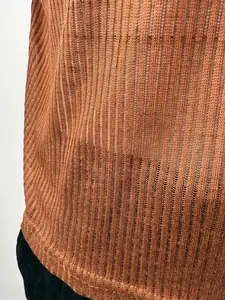 Macro detail showing the intricate sheer ribbed knit texture of a brown summer top