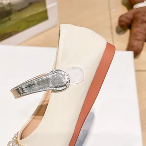 Detalle de zapatos Mary Jane crema para niña con cierre de velcro plateado y perlas