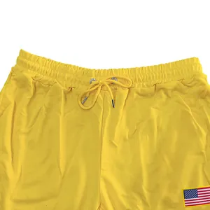 Détail du pantalon de jogging jaune ample avec écusson drapeau américain et cordon de serrage