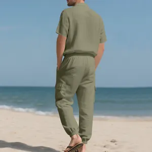 Vista trasera de un hombre con conjunto de lino verde oliva, camisa y pantalón cargo en playa.