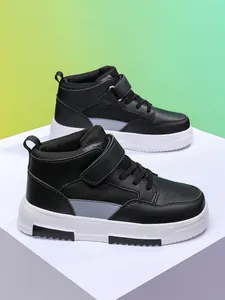Vue détaillée de baskets montantes noires pour enfants sur des plateformes géométriques.