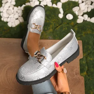 Vista detallada de mocasines plateados para mujer con números en relieve y cadena dorada.