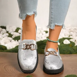 Detalle de mocasines plateados para mujer con suela gruesa y cadena dorada de metal