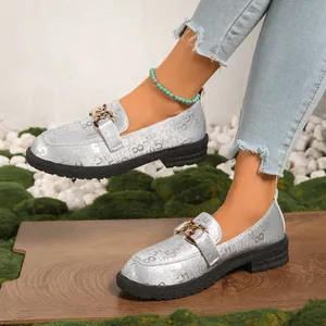 Detalle de los mocasines plateados con hebilla dorada y estampado de números negros