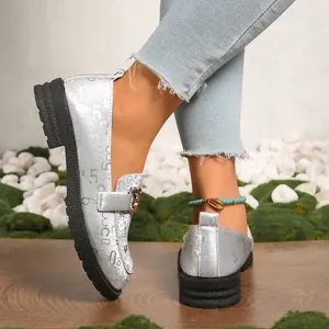 Vista detallada de mocasines con plataforma plateados para mujer con vaqueros y una tobillera