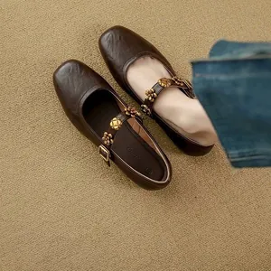 Detail of dark brown Mary Jane flats with decorative gold metal flowers on the strap
