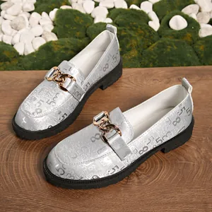 Vista detallada de mocasines plateados para mujer con patrones numéricos y cadena dorada.