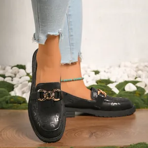 Vista detallada de mocasines negros para mujer con cadena dorada y números en relieve