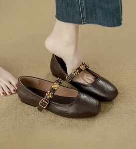 Close-up view of brown Mary Jane flats with decorative gold flower buckles.