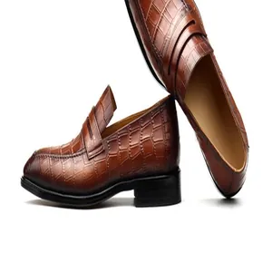 Gedetailleerd overzicht van bruine leren loafers voor heren met krokodillenmotief.