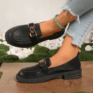 Primer plano de mocasines negros con plataforma, cadena dorada y patrón de cuero