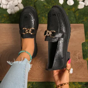 Primer plano detallado de mocasines negros con plataforma, cadena de oro y diseño