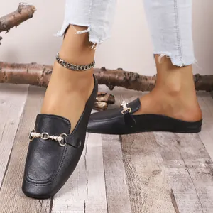 Detalle de mocasines negros cerrados con adorno de perlas y hebilla metal