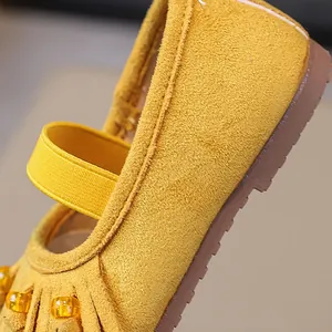 Detailed view of yellow suede Mary Jane shoes for girls with fringe and beads decoration.