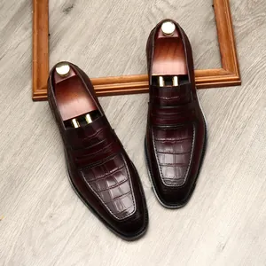 Heren loafers van bordeauxrood leer met krokodillenprint en houten schoenspanners.