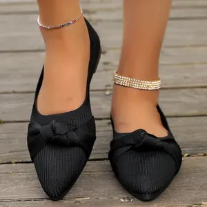Primo piano di ballerine in maglia nera a punta con un elegante dettaglio a fiocco annodato