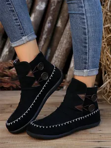 Side detail of women's black flat ankle boots with decorative buttons and stitching