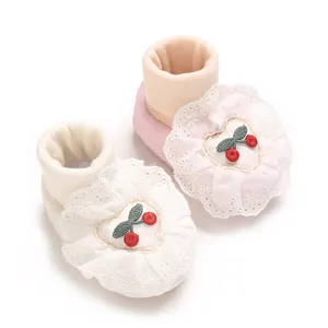 Detail view of baby princess shoes with delicate lace flowers and cherry embroidery