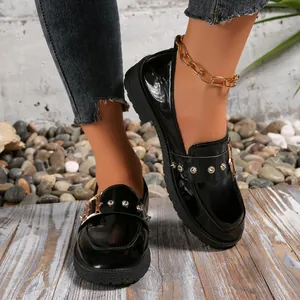Primer plano de mocasines de plataforma en charol negro para mujer con tachuelas.
