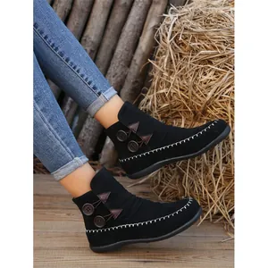 Women's black suede flat ankle boots with button details and decorative white stitching
