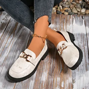 Detalle de mocasines blancos con plataforma, cadena dorada y patrones en relieve