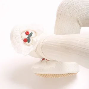 Detailed close-up of newborn baby sock shoes with delicate lace and cherry embroidery