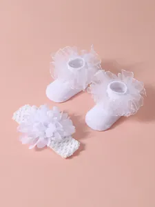 Vista detallada de elegantes calcetines de encaje blanco y diadema para bebé