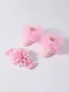 Detalle de calcetines rosa para bebé con volantes de encaje y diadema de flores a juego