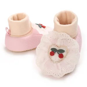 Close-up of soft baby girl sock shoes with lace ruffle and embroidered cherry heart