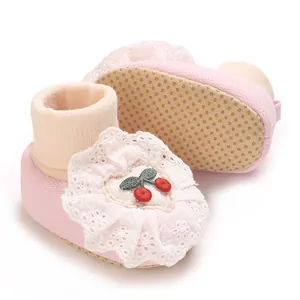 Close-up detail of pink newborn baby sock shoes with lace and cherry embroidery