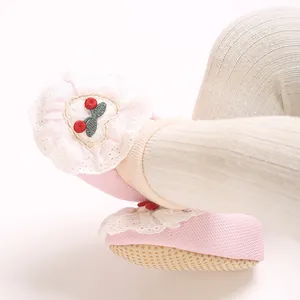 Close-up of soft pink baby sock shoes featuring delicate lace and cherry embroidery.