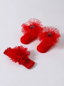 Detalle macro de lindos calcetines rojos para bebé con encaje y diadema floral a juego set