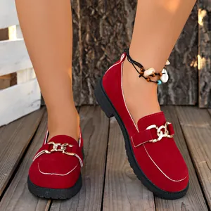 Elegantes mocasines rojos de ante para mujer con cadena dorada en terraza de madera