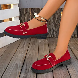 Primer plano de mocasines de gamuza roja con hebilla dorada y suela gruesa en madera