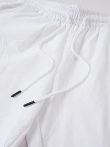 Detail der weißen Baumwoll-Leinen-Jogger mit elastischem Bund und Kordelzug-Struktur.