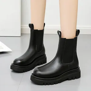 Vista detallada de botines Chelsea de cuero negro con una suela track de tendencia.