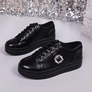 Detail van zwarte platform sneakers met een glanzende vierkante kristallen gesp