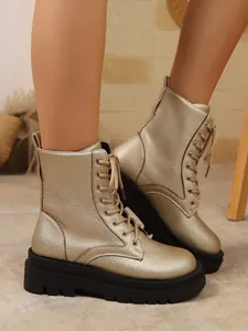 Detalle que muestra la textura metálica dorada y el diseño de cordones de los botines bajos