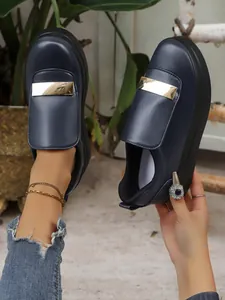 Close-up of navy blue platform loafers with a stylish gold metal bar and thick sole.