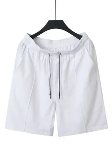 Detailed view of white linen drawstring shorts with elastic waistband and black-tipped cords.