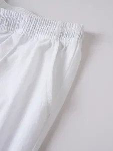 Detailed close-up of white linen beach shorts showing elastic waistband and pocket texture.