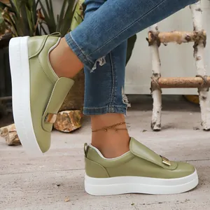 Close-up of olive green platform sneakers with a thick white sole and gold buckle.