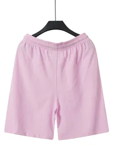 Front view of solid pink men's summer beach shorts hanging on a black clothes hanger