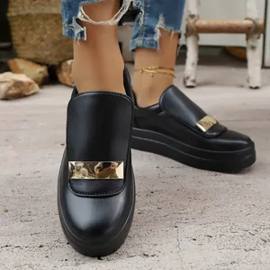 Close-up detail of stylish black platform loafers featuring a decorative gold buckle.