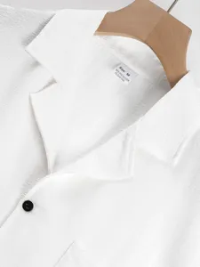 Detailed close-up of white textured casual shirt collar with size M label and button
