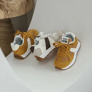 Close-up view of stylish retro mesh sneakers for kids in mustard yellow and beige tones