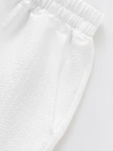 Close-up detail of white men's shorts showing textured seersucker fabric and waistband
